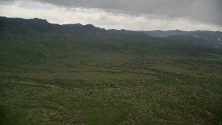 5.5K aerial stock footage of approaching green hills, heavy clouds above, Wasatch Range, Utah Aerial Stock Footage | AX130_125E