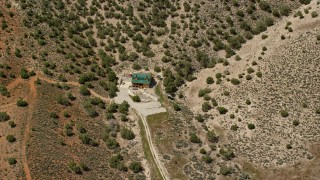 AX130_155 - 5.5K aerial stock footage approach and tilt to isolated home, dry hills, Sterling, Utah