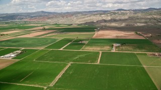 5.5K aerial stock footage of passing by farmland, brown hills, Richfield, Utah Aerial Stock Footage | AX130_190