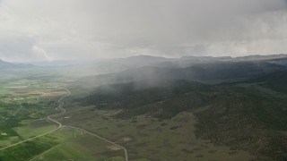 5.5K aerial stock footage of flying by rain falling on mountains, trees, near farming community, Fishlake National Forest, Utah Aerial Stock Footage | AX130_215