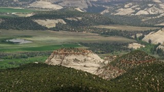 5.5K aerial stock footage of flying by rural homes, fields, pond, and flat-topped mountain, Boulder, Utah Aerial Stock Footage | AX130_369E