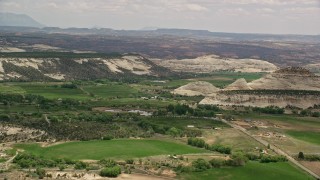 5.5K aerial stock footage of small mountains, green fields, rural town around a pond, Boulder, Utah Aerial Stock Footage | AX130_371E