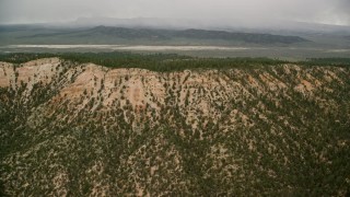 5.5K aerial stock footage of flying by mountain ridge, trees, dry lake in the distance, Bryce Canyon National Park, Utah Aerial Stock Footage | AX130_420E