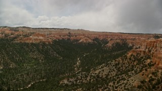 AX130_453E - 5.5K aerial stock footage of wide canyon with trees, surrounded by hoodoos, buttes; Bryce Canyon National Park, Utah