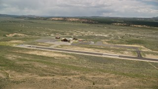 5.5K aerial stock footage of approaching single prop plane, helicopters, near wooden hangar, Bryce Canyon Airport, Utah Aerial Stock Footage | AX130_498E