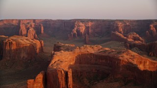 5.5K aerial stock footage of flying by rock formations and Hunt's Mesa, Monument Valley, Utah, Arizona, sunset Aerial Stock Footage | AX133_199E