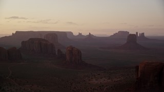 5.5K aerial stock footage of passing by buttes and mesas in hazy Monument Valley, Utah, Arizona, twilight Aerial Stock Footage | AX133_212