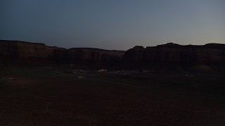 AX134_073 - 5.5K aerial stock footage of flying by small town at base of Oljeto Mesa, Goulding, Utah, twilight