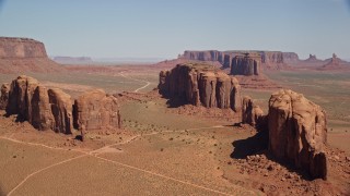 5.5K aerial stock footage of approaching three buttes in a hazy desert valley, Monument Valley, Utah, Arizona Aerial Stock Footage | AX135_030