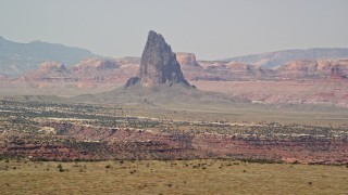 5.5K aerial stock footage of flying by tall butte in a hazy desert valley, Monument Valley, Utah, Arizona Aerial Stock Footage | AX135_185