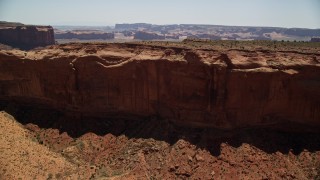 AX136_012E - 5.5K aerial stock footage of flying over Mitchell Mesa to approach distant buttes in Monument Valley, Utah, Arizona