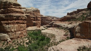 AX136_097E - 5.5K aerial stock footage of flying low though Grand Gulch, over slopes and plants, Grand Gulch Primitive Area, Utah