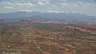 5.5K aerial stock footage of a wide view of rock formations, snow-capped mountains, Arches National Park, Utah Aerial Stock Footage | AX137_006E