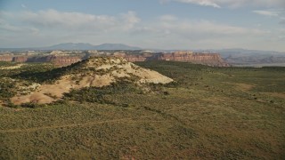 5.5K aerial stock footage of approaching a rock overlooking a canyon, mesas in the background in Moab, Utah Aerial Stock Footage | AX138_244E