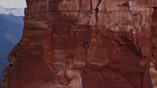 AX138_422 - 5.5K aerial stock footage of a rock climber on the side of Castleton Tower, Moab, Utah, sunset