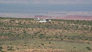 AX139_033E - 5.5K aerial stock footage track a Tecnam P2006T flying over desert valley, Grand County, Utah