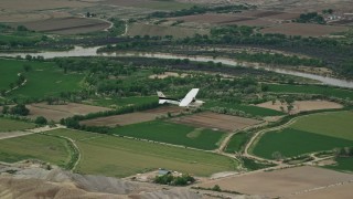 5.5K aerial stock footage of tracking Cessna over farmland and desert hills, Green River, Utah Aerial Stock Footage | AX139_098