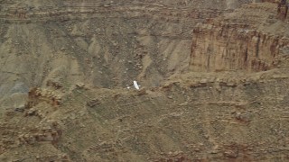 AX139_101E - 5.5K aerial stock footage of tracking a Cessna flying by desert buttes, Emery County, Utah