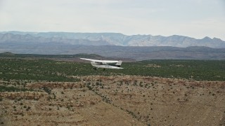 AX139_108E - 5.5K aerial stock footage track a Cessna flying by desert mesas, Emery County, Utah