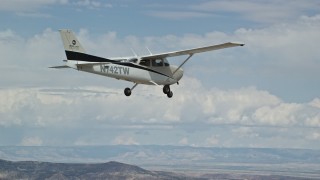 AX139_137E - 5.5K aerial stock footage of flying beside a Cessna high above desert, partly cloudy skies, Emery County, Utah