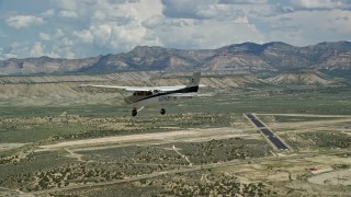 AX139_159E - 5.5K aerial stock footage of tracking a Cessna flying over desert and approaching Buck Davis Field, Utah