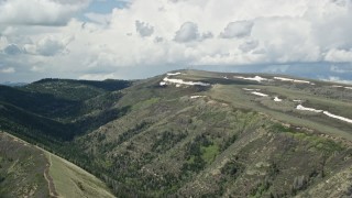 5.5K aerial stock footage of flying by mountains with snow patches beneath partly cloudy skies, Utah County, Utah Aerial Stock Footage | AX140_035E