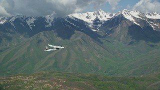 AX140_122E - 5.5K aerial stock footage of tracking a Tecnam P2006T near snowy mountain peak, Wasatch Range, Utah