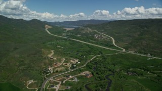 AX140_185E - 5.5K aerial stock footage of a view of Highway 40 through green mountain foothills, Heber City, Utah