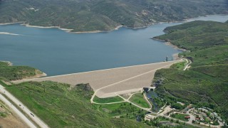 5.5K aerial stock footage of orbiting dam surrounded by green hills near highway, Jordanelle Dam, Utah Aerial Stock Footage | AX140_191E