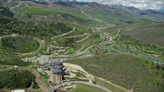 AX140_199E - 5.5K aerial stock footage of flying over condos to approach town center, green mountains, Park City, Utah