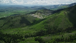 AX140_215E - 5.5K aerial stock footage approach luge, bobsled, skeleton track from green mountains, Utah Olympic Park