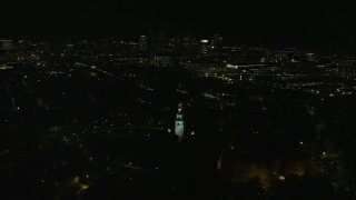 AX141_229E - 5.5K aerial stock footage of Dorchester Heights Monuments, lights of downtown skyline, South Boston, Massachusetts, night