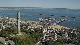 AX143_226E - 5.5K aerial stock footage orbiting Pilgrim Monument, small coastal town, Provincetown, Massachusetts