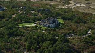 AX144_113E - 5.5K aerial stock footage approaching upscale home, dense trees, Nantucket, Massachusetts