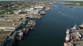 AX144_196E - 6k aerial stock footage flying over fishing boats, waterfront warehouses, New Bedford, Massachusetts