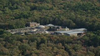 AX144_211 - 6k aerial stock footage flying by water treatment plant, dense trees, Dartmouth, Massachusetts