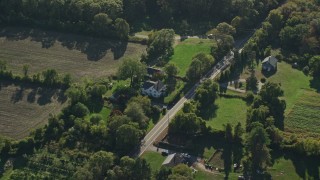 AX144_219 - 6k aerial stock footage approaching small farms, tilt down over trees, Little Compton, Rhode Island