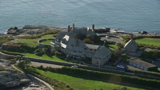 AX144_250E - 6k aerial stock footage orbiting oceanfront mansion, coastal cliffs, Newport, Rhode Island