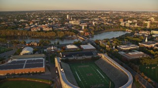 AX146_041E - 6k aerial stock footage approaching Harvard Stadium and Harvard University, Massachusetts, sunset