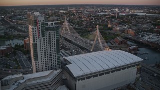 AX146_087E - 6k aerial stock footage flying over TD Garden, approaching Zakim Bridge, Boston, Massachusetts, sunset