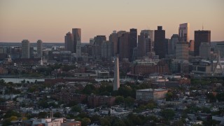 AX146_090E - 6k aerial stock footage orbiting the Bunker Hill Monument, skyline, Charlestown, Massachusetts, sunset