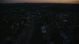 AX146_149E - 6k aerial stock footage flying over Columbus Avenue, train tracks, Jamaica Plain, Massachusetts, twilight