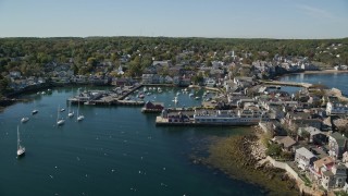 AX147_117E - 6K aerial stock footage flying over harbor toward coastal town, Rockport, Massachusetts