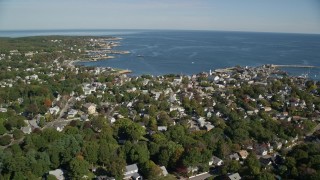 AX147_123E - 6K aerial stock footage flying along small coastal town with church in the distance, Rockport, Massachusetts