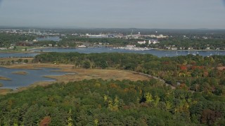 AX147_169 - 6K aerial stock footage flying over marshland and forest toward harbor in autumn, Rye, New Castle, New Hampshire