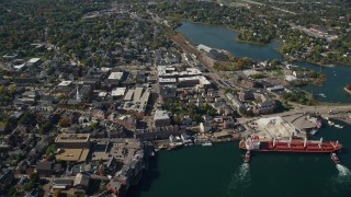 6K aerial stock footage flying by coastal town and a cargo ship in autumn, Portsmouth, New Hampshire Aerial Stock Footage | AX147_203E