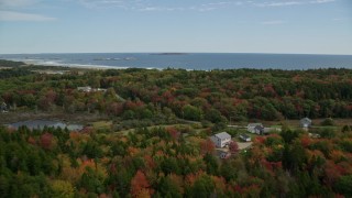 6K aerial stock footage flying over rural homes, colorful forest, approaching the beach, Phippsburg, Maine Aerial Stock Footage | AX147_383E