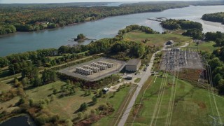 AX148_001 - 6K aerial stock footage flying by an electrical substation near a river, autumn, Wiscasset, Maine