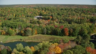 6K aerial stock footage flying over colorful forest, approach small warehouse, autumn, Newcastle, Maine Aerial Stock Footage | AX148_008