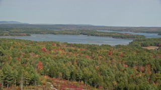 AX148_026E - 6K aerial stock footage flying over colorful forest, by watchtower, reveal Broad Cove, Bremen, Maine